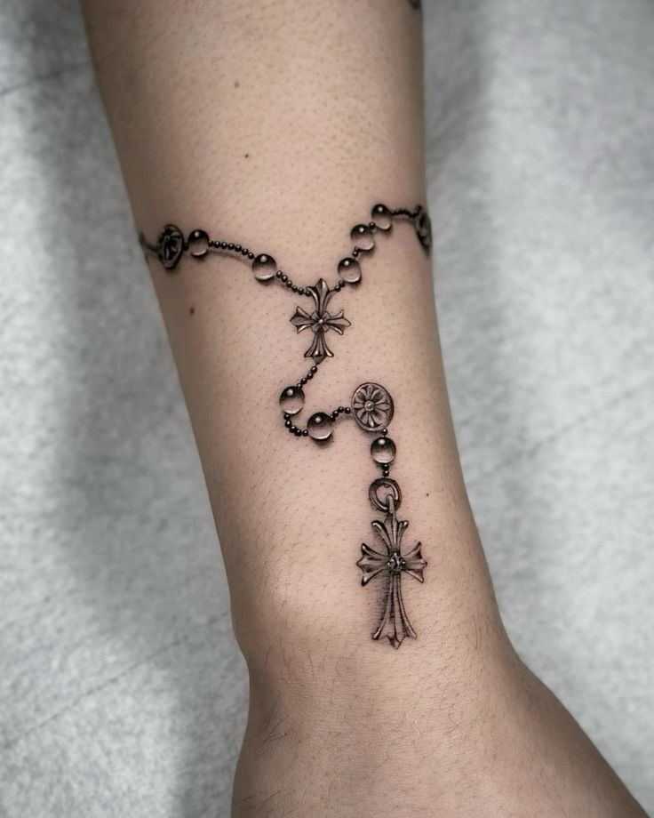 a woman's foot with a rosary and cross tattoo on the side of her leg