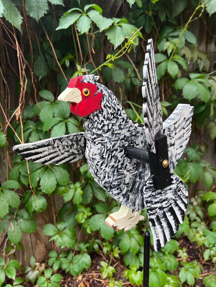 a bird that is sitting on top of a pole in front of some bushes and trees