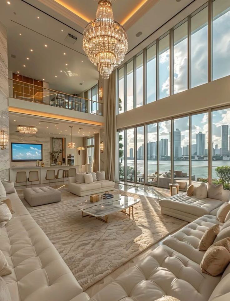 a living room filled with lots of white furniture and large windows overlooking the city skyline