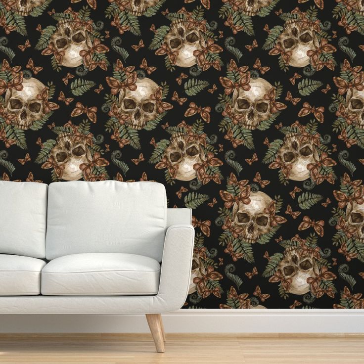 a white couch sitting in front of a wall with skulls and flowers on it's side