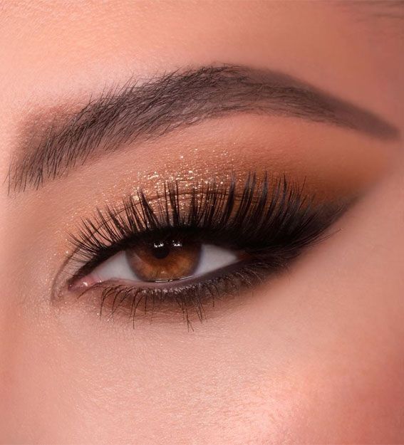 a woman's eye with long lashes and brown eyeshadow