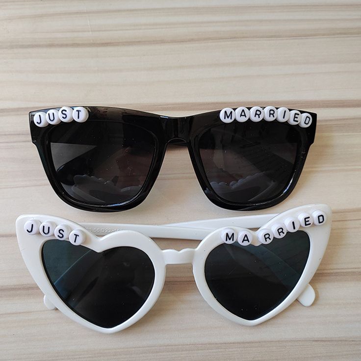 two pairs of sunglasses with the words just married written on them, sitting on a wooden surface