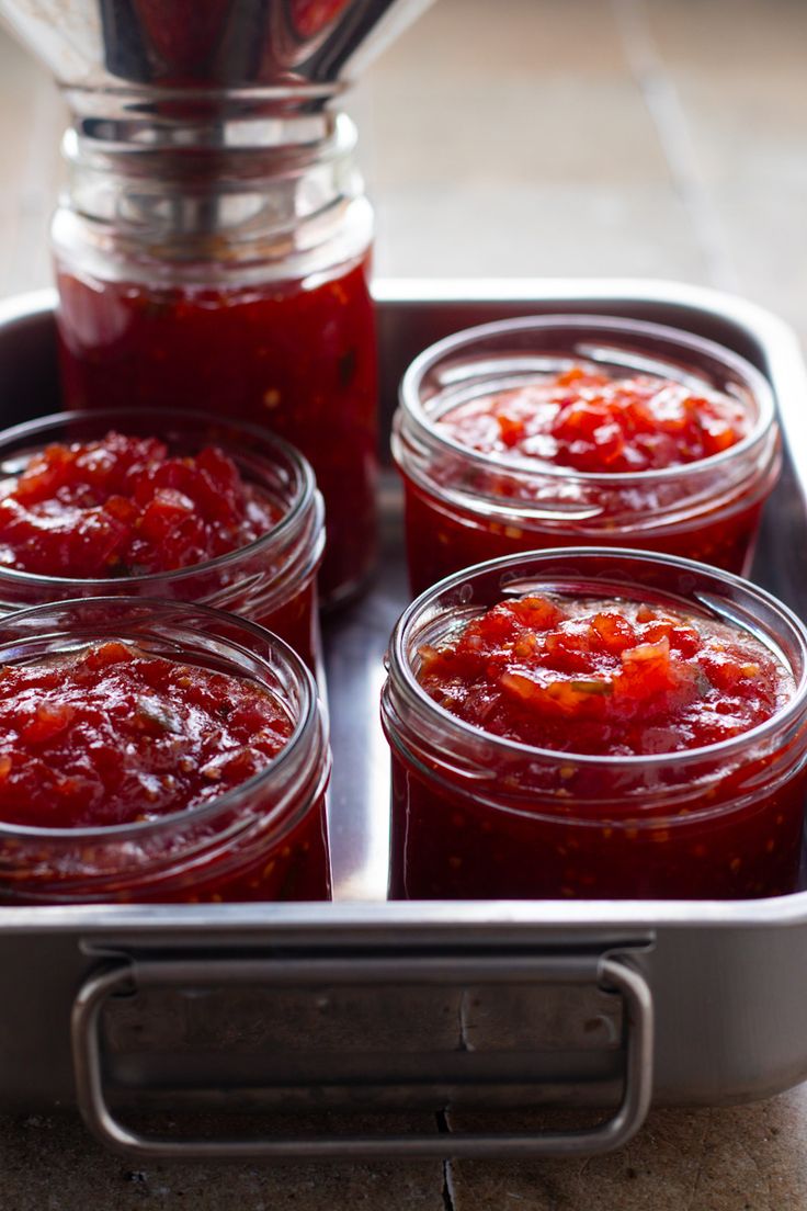 four jars filled with jam sitting on top of a metal tray