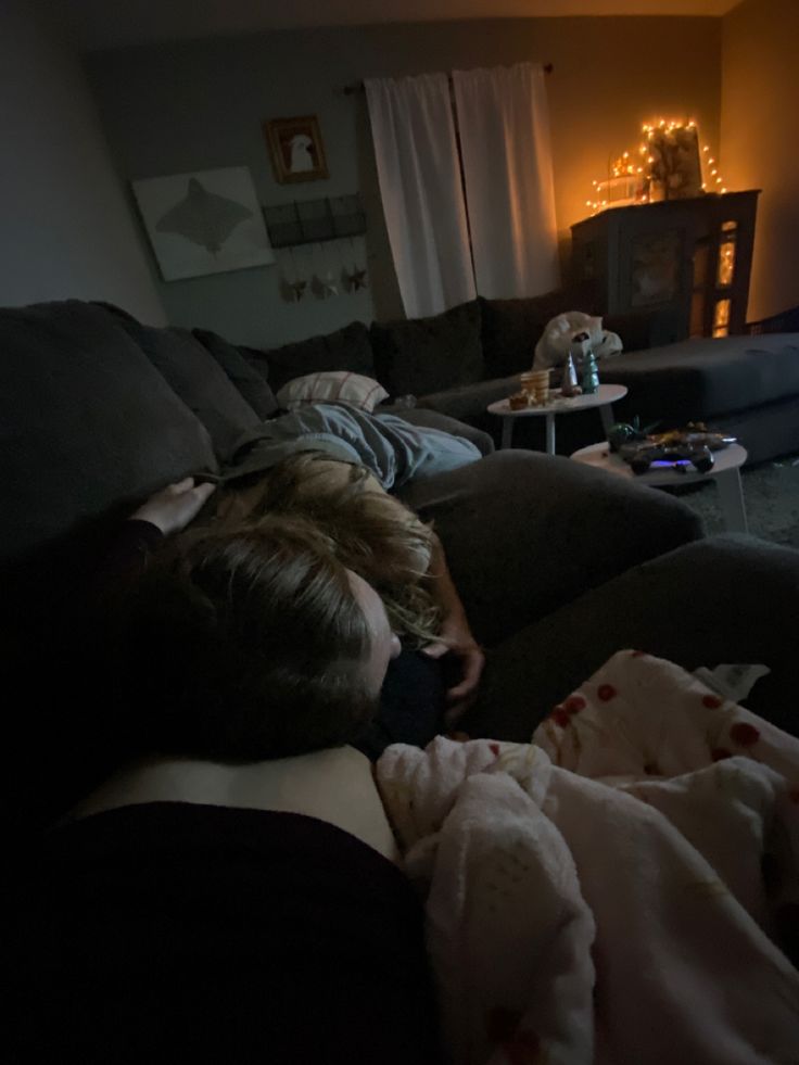 a woman laying on top of a couch in a living room next to a tv