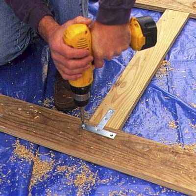 a man using a drill to cut wood planks with a power tool on the ground