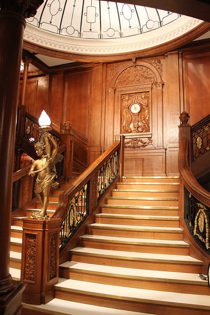 an ornate staircase leading up to a clock on top of a wooden paneled wall