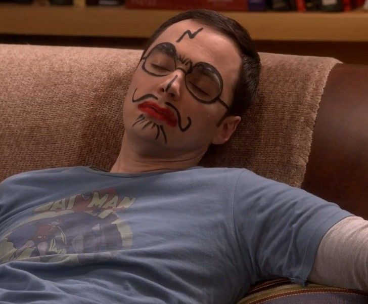 a man laying on top of a couch with his face painted to look like he is sleeping