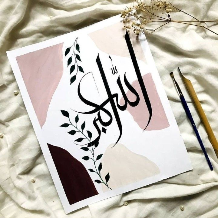 an arabic calligraphy is displayed on a sheet with two pencils next to it