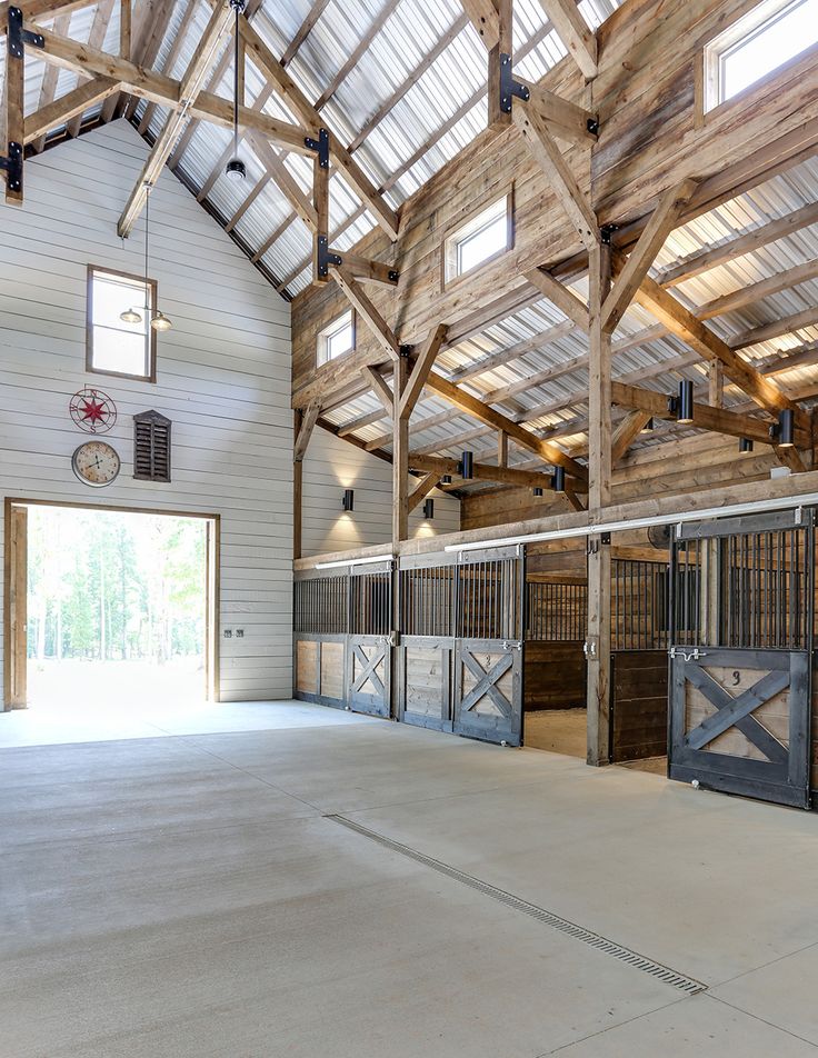 the inside of a barn with several stalls and doors open to let in plenty of light