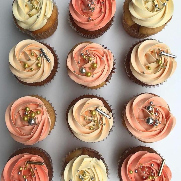 twelve cupcakes with pink frosting and gold decorations