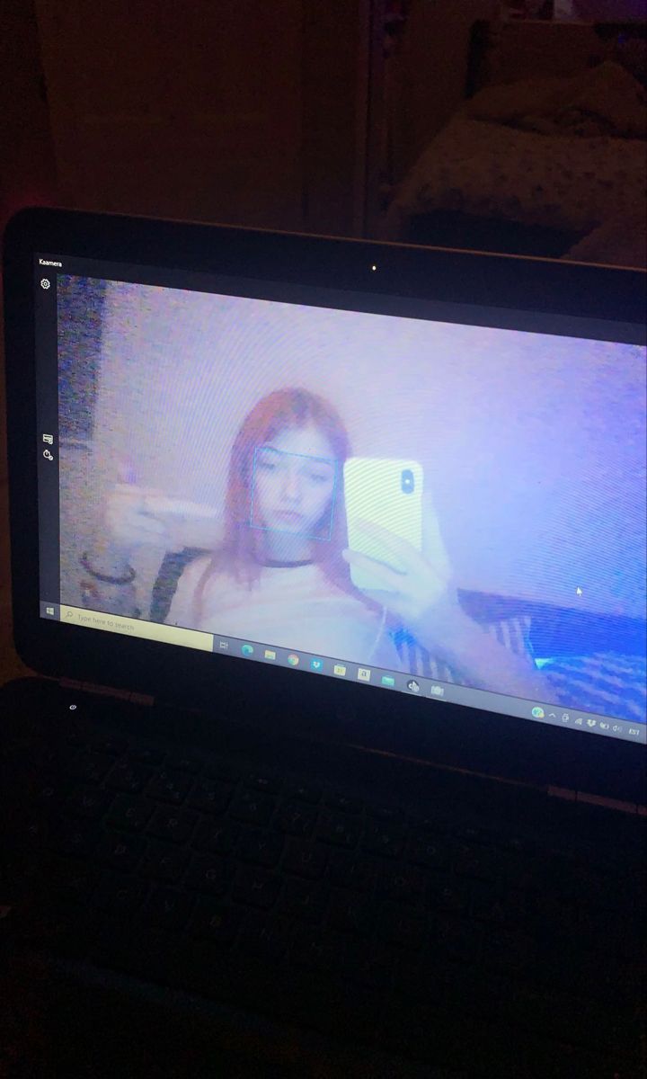 a laptop computer sitting on top of a table with a woman's face on the screen