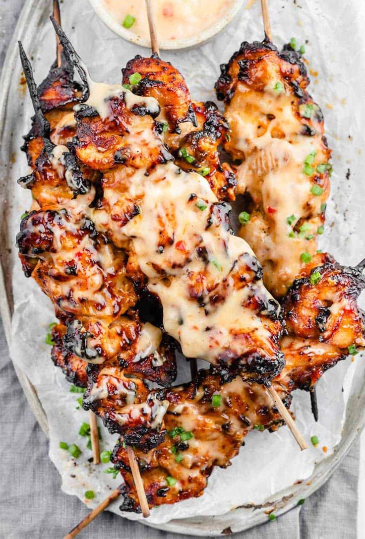 grilled chicken skewers on a plate with dipping sauce