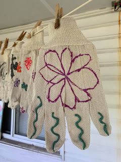 several gloves hanging on a clothes line with flowers and leaves painted on them, along with other handmade items