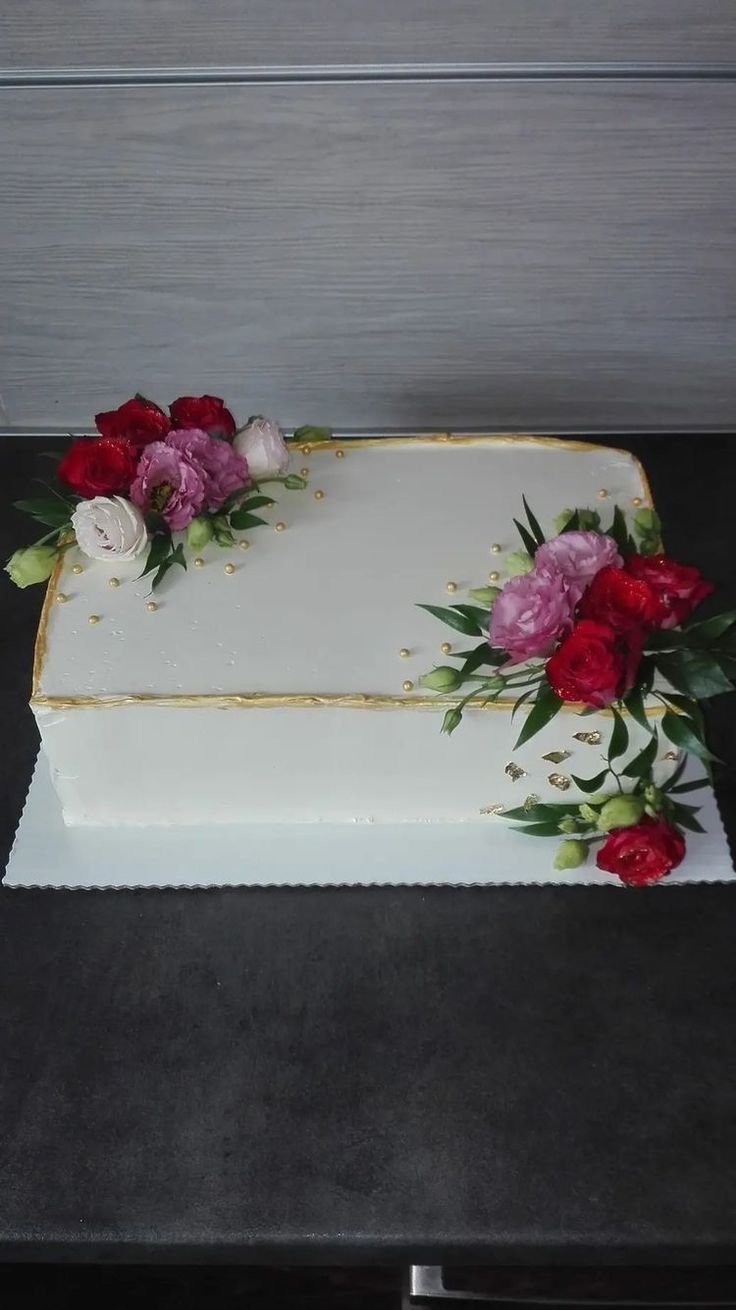 a white cake with red and pink flowers on it