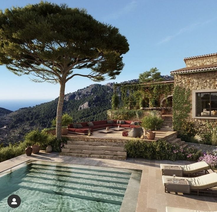 an outdoor swimming pool surrounded by greenery and stone steps leading up to the house