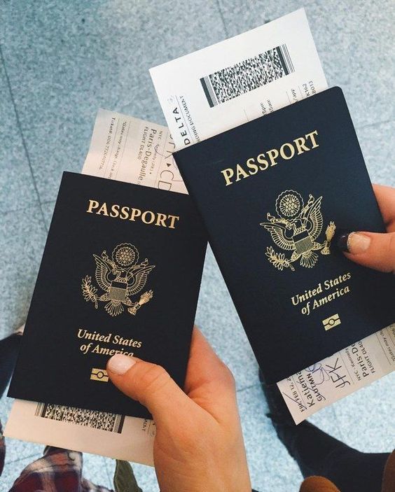 two people holding up their united states passports in front of each other with both hands