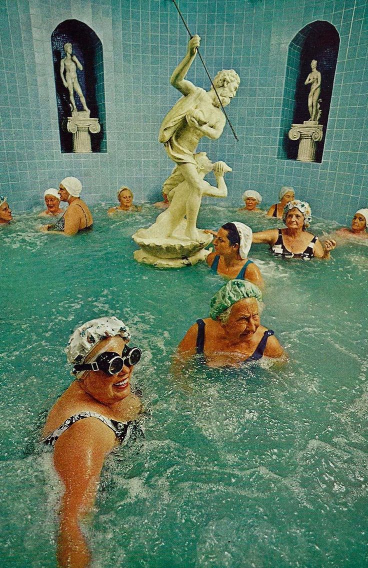 several people in a swimming pool with statues