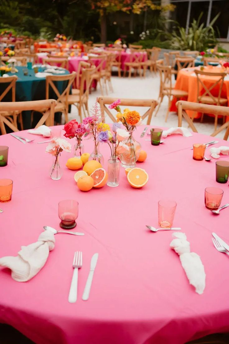 the table is set with oranges and pink napkins