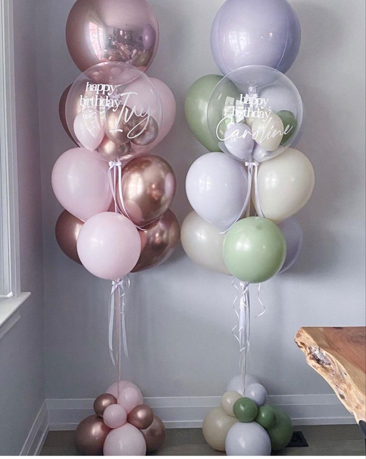 balloons and streamers with happy birthday messages on them in pastel colors are displayed against a white wall