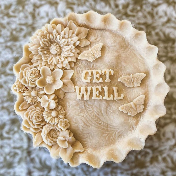 the words get well written in carved letters are surrounded by flowers, butterflies and leaves