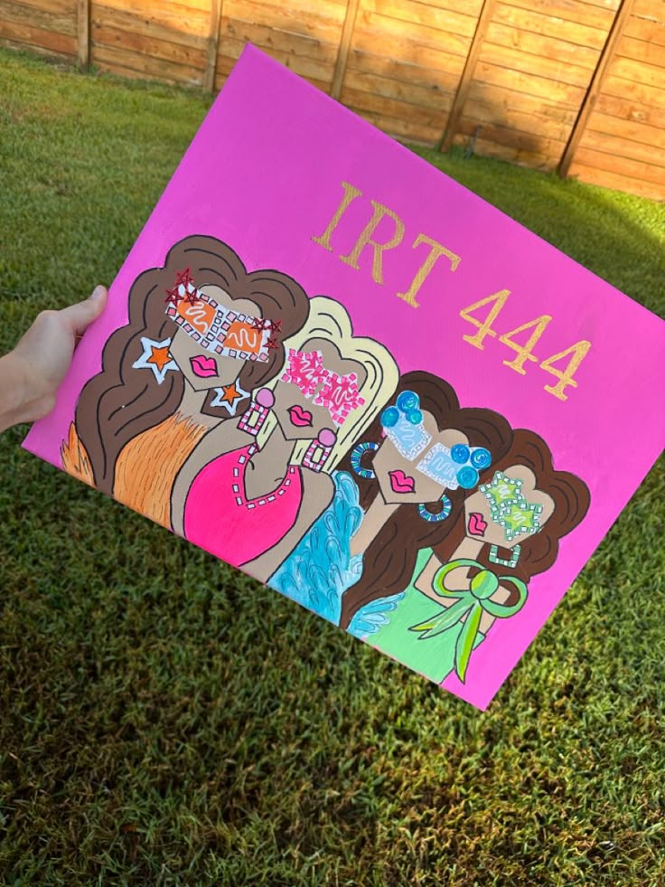 a person holding up a pink sign that says 447 with two girls on it