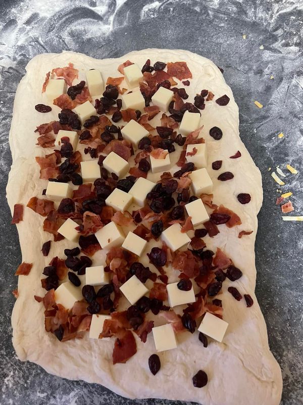 an uncooked pizza with cheese and bacon on it