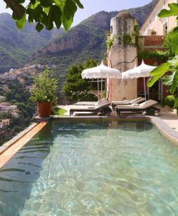 an outdoor swimming pool with chaise lounge chairs and umbrellas overlooking the city below