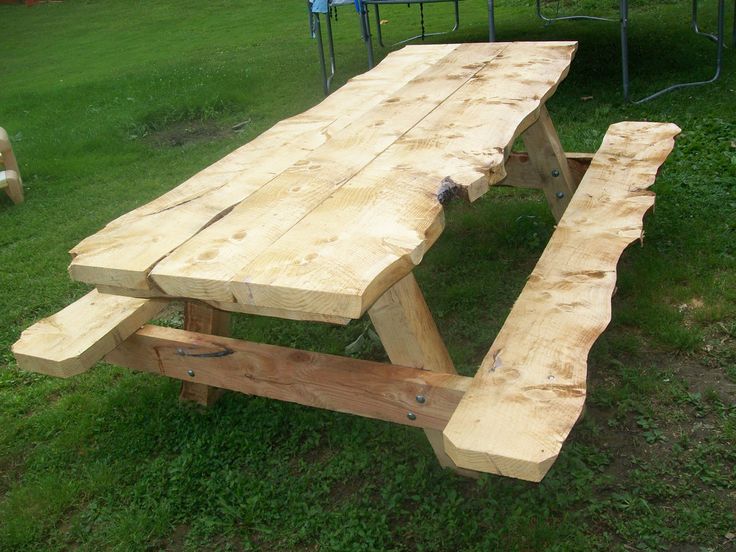 a wooden picnic table sitting on top of a lush green field