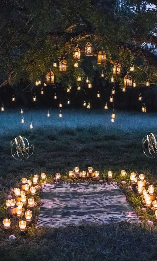 candles are arranged in the shape of a heart on a blanket under a large tree