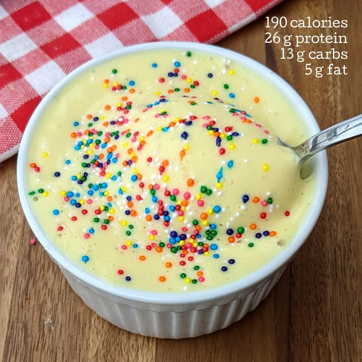 a bowl filled with cake batter and sprinkles on top of a wooden table