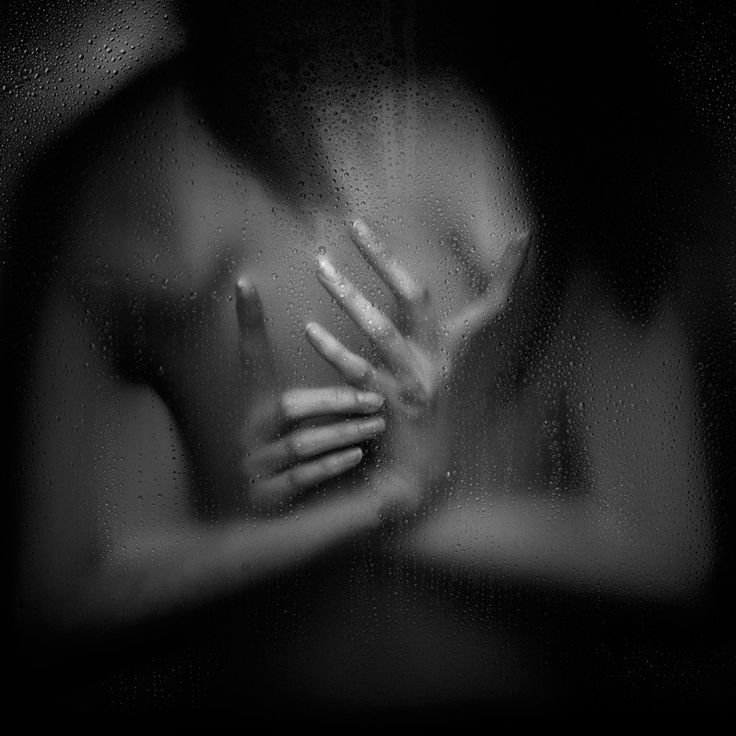 black and white photograph of woman's hands in front of rain streaked glass window