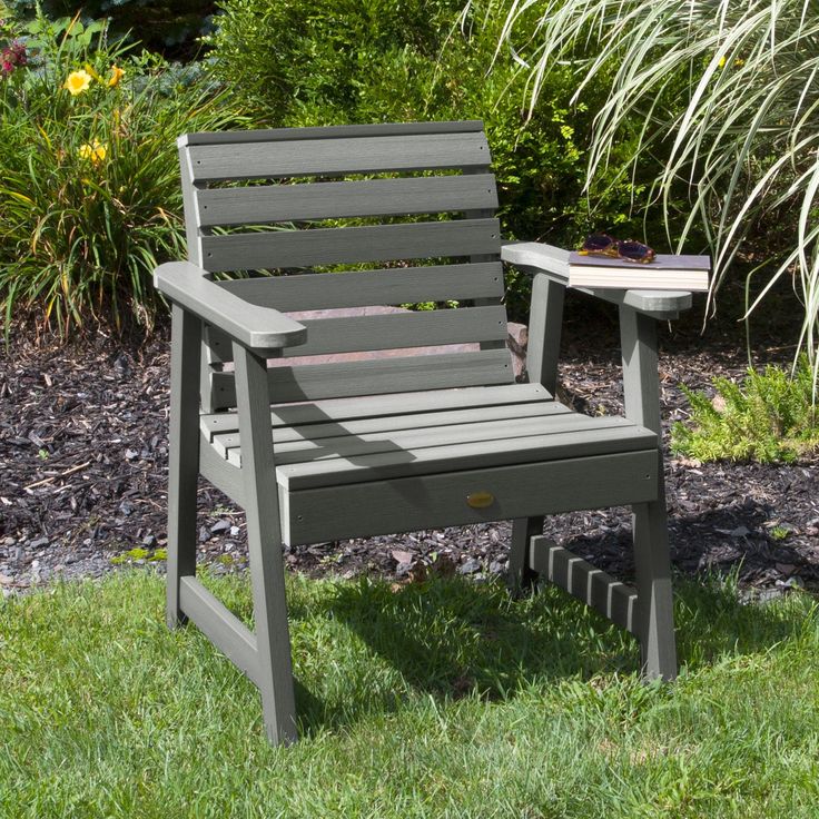 a wooden chair sitting in the grass next to a small table with a cup on it