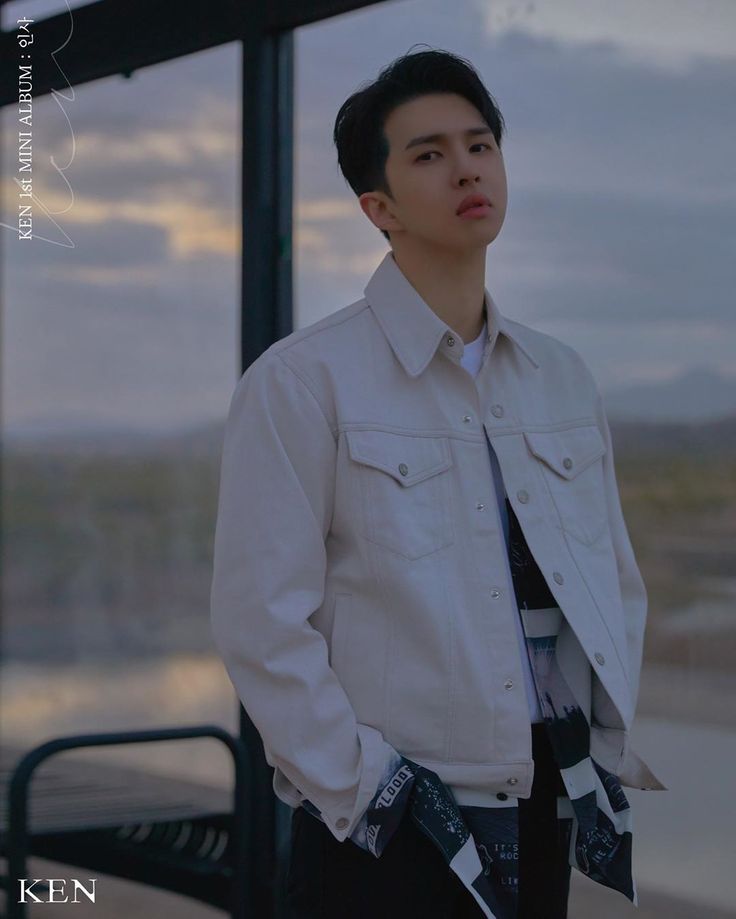 a young man standing in front of a window wearing a white jacket and black tie