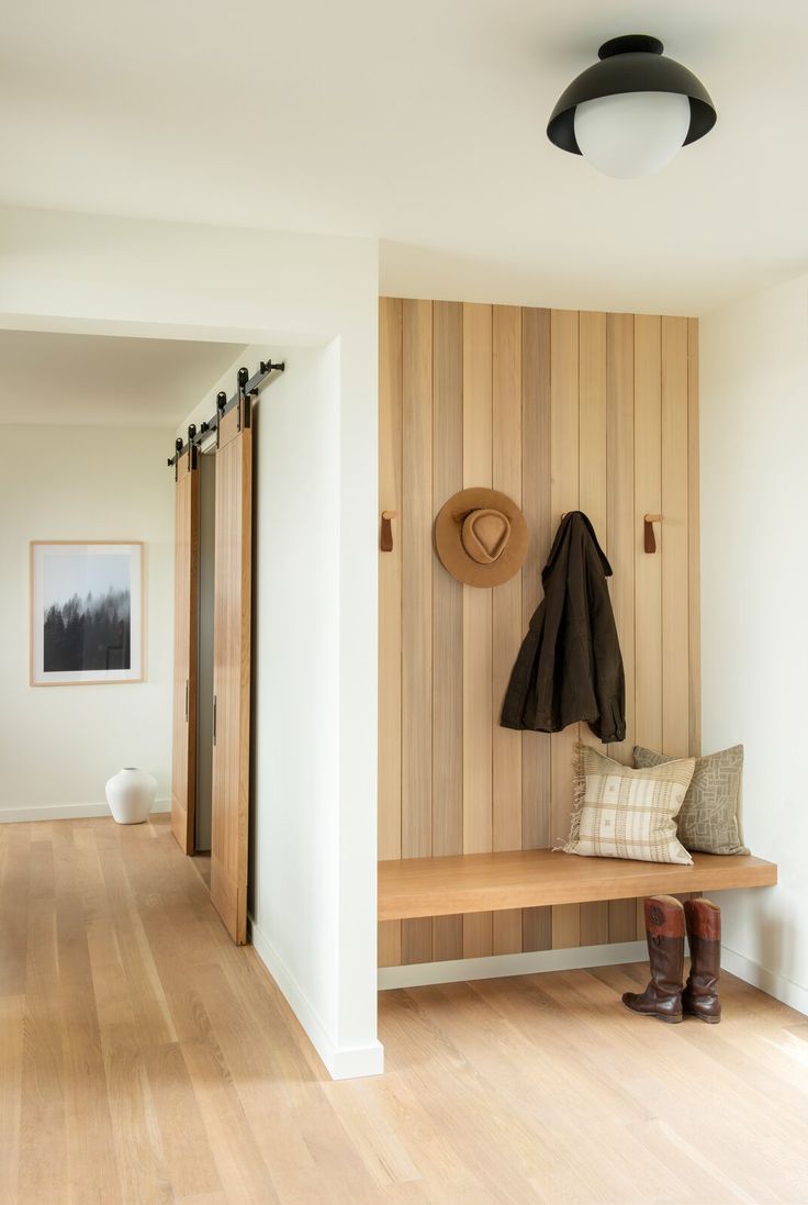 a wooden bench sitting on top of a hard wood floor next to a coat rack