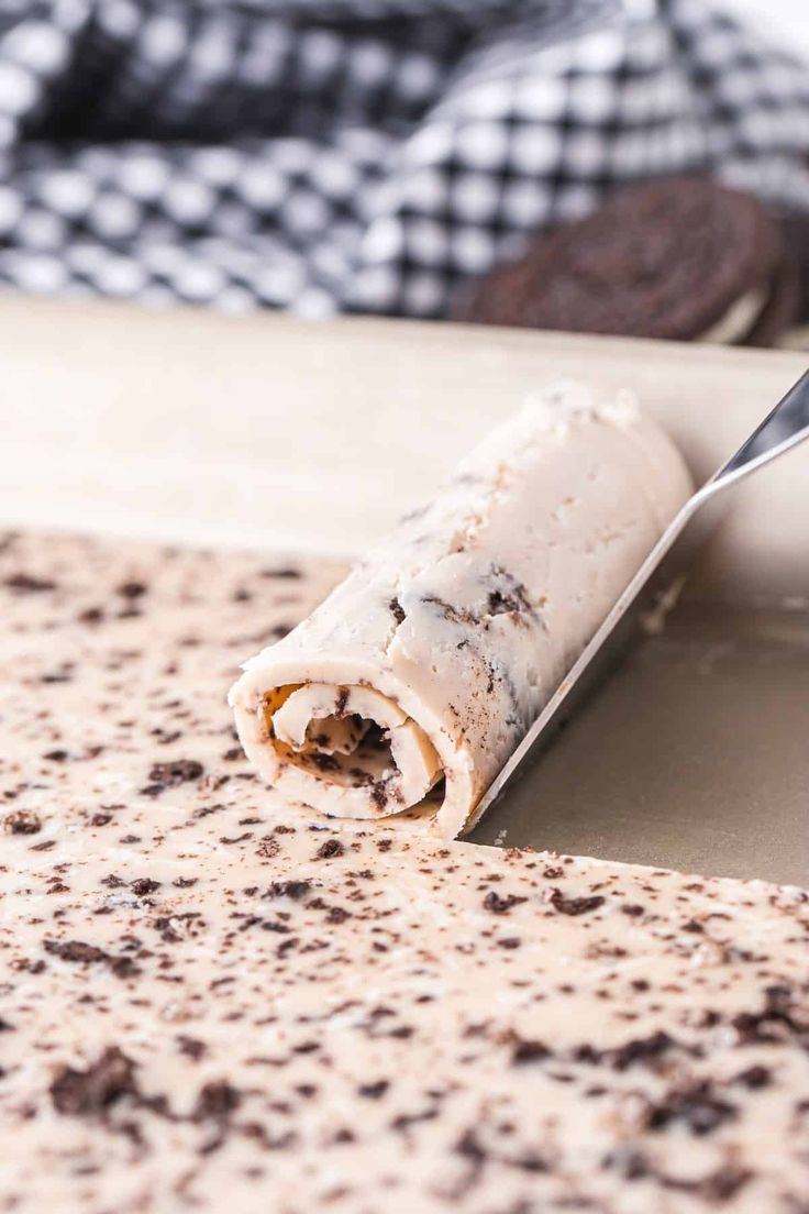 a knife is cutting into a piece of food on a counter top with chocolate chip cookies in the background