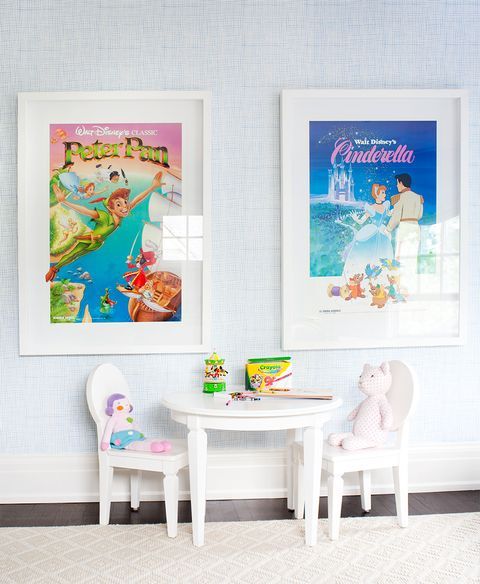 two children's posters hang on the wall next to a small table and chairs