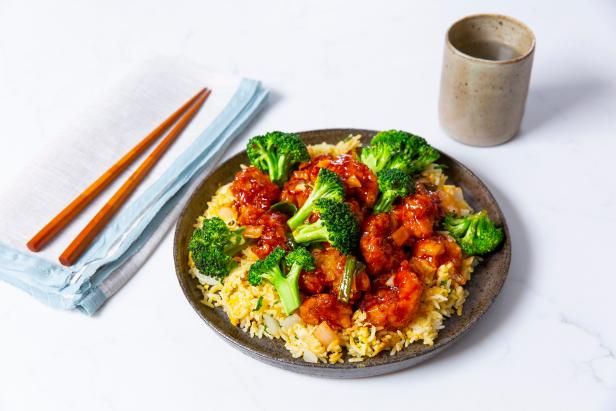 a plate with rice, broccoli and chicken on it next to chopsticks