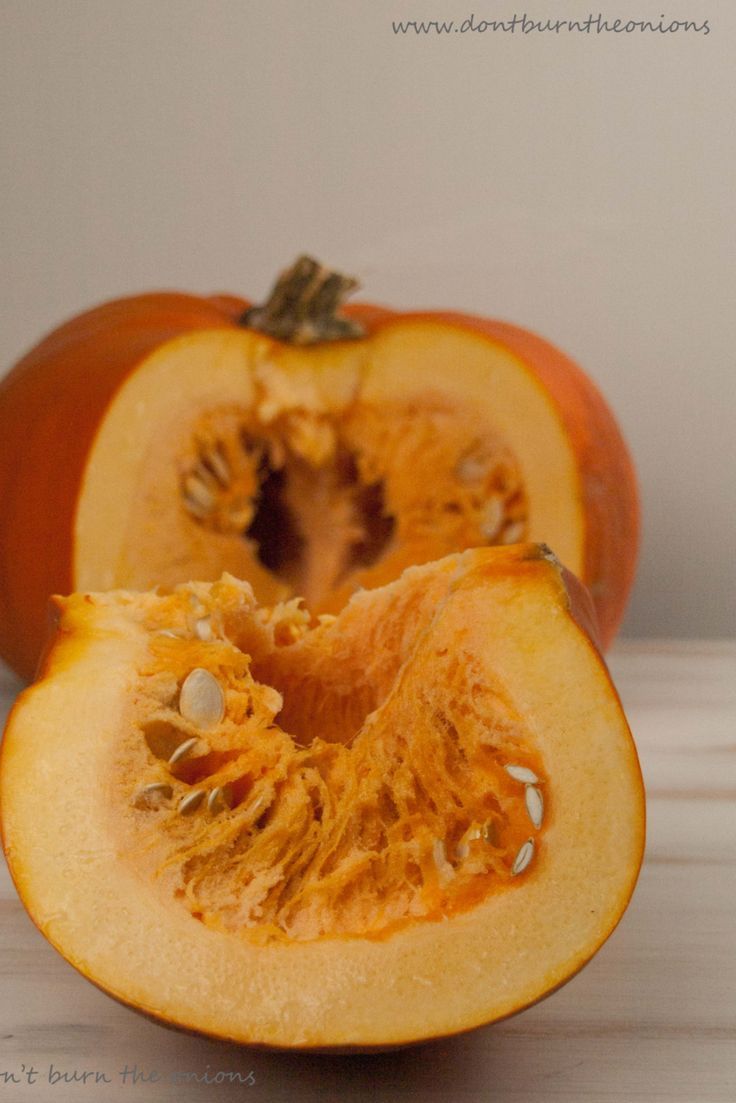 an orange cut in half sitting on top of a wooden table next to a white wall