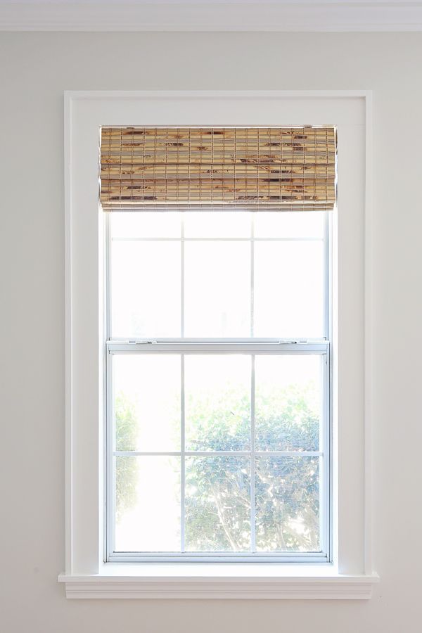 a window with a bamboo blind on it in a white room next to a toilet