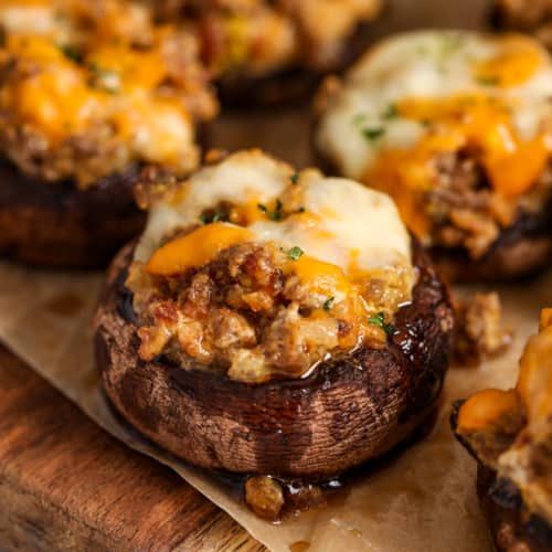 stuffed mushrooms with cheese and meat on a cutting board