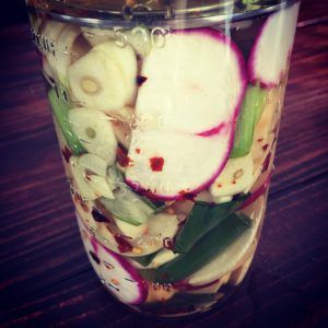 a glass filled with sliced vegetables on top of a wooden table