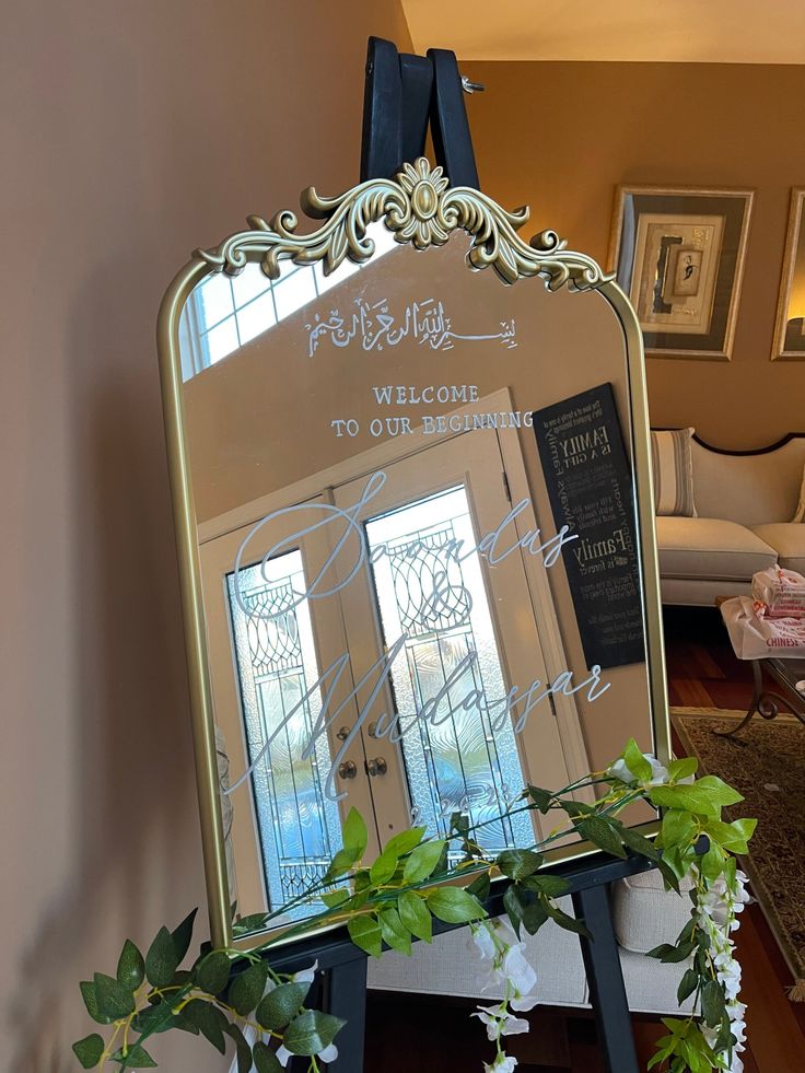 there is a mirror with writing on it and flowers in the vase next to it