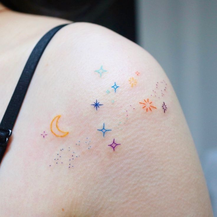 the back of a woman's shoulder with colorful stars and moon tattoos on it