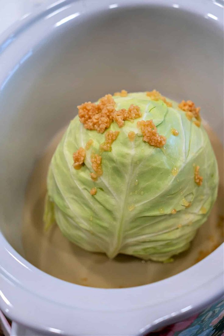 a head of cabbage in a bowl with some brown stuff on it's surface