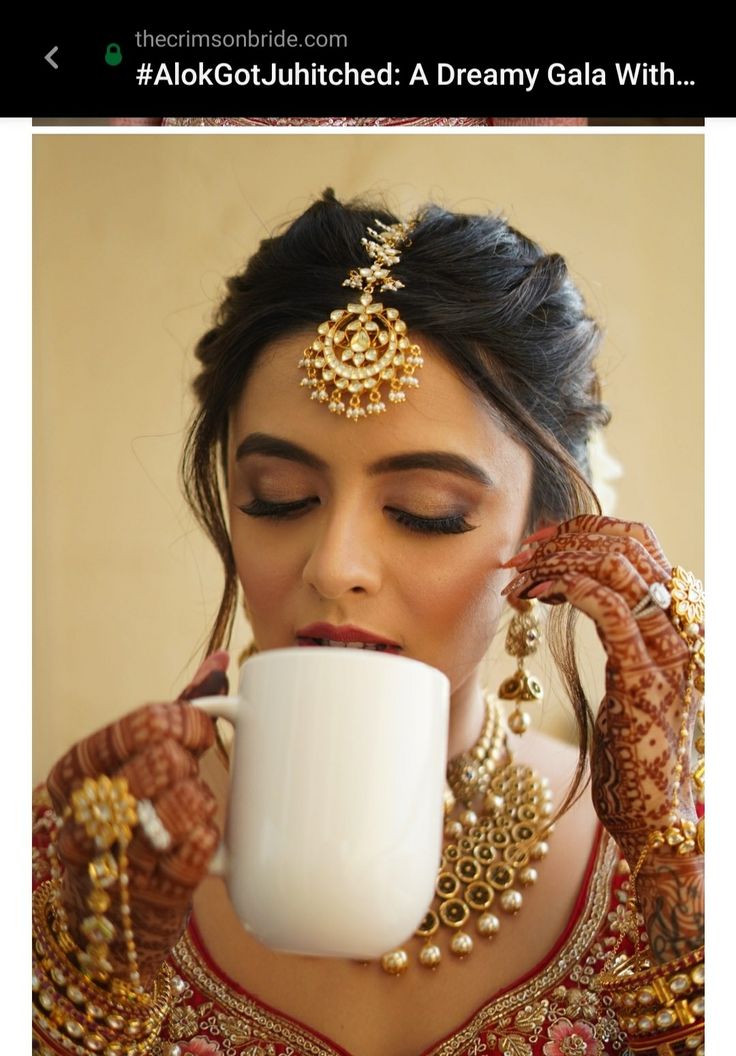 a woman drinking out of a cup while wearing jewelry