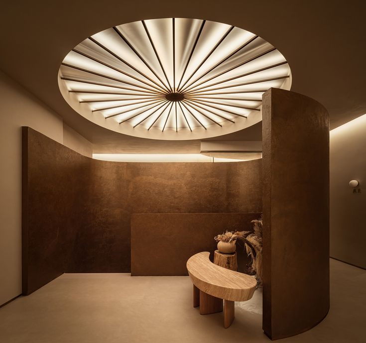 a circular light fixture hangs above a bench in the middle of a room with concrete walls