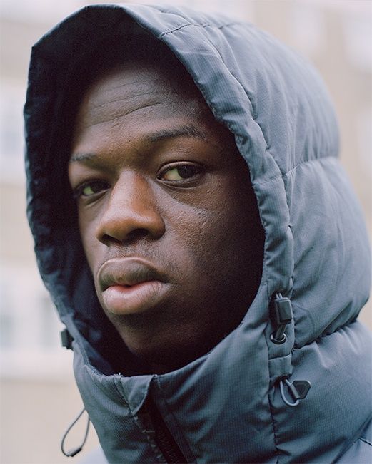 a man in a hooded jacket looking at the camera with an intense look on his face