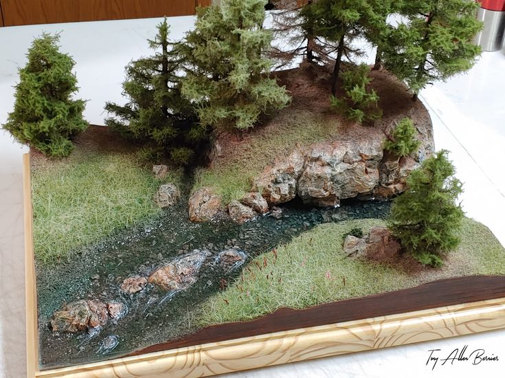 a model of a river running through a forest with rocks and trees on the side