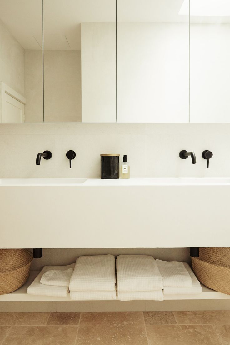 a bathroom with two sinks and mirrors in it's center area, along with towels on the floor