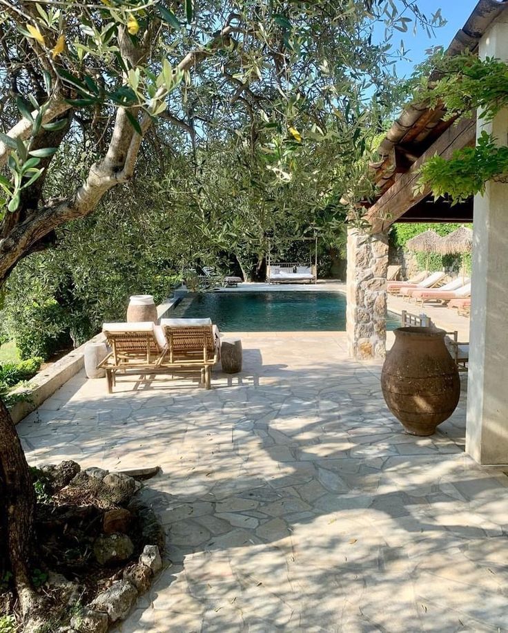 an outdoor patio with chairs and tables next to a swimming pool surrounded by olive trees